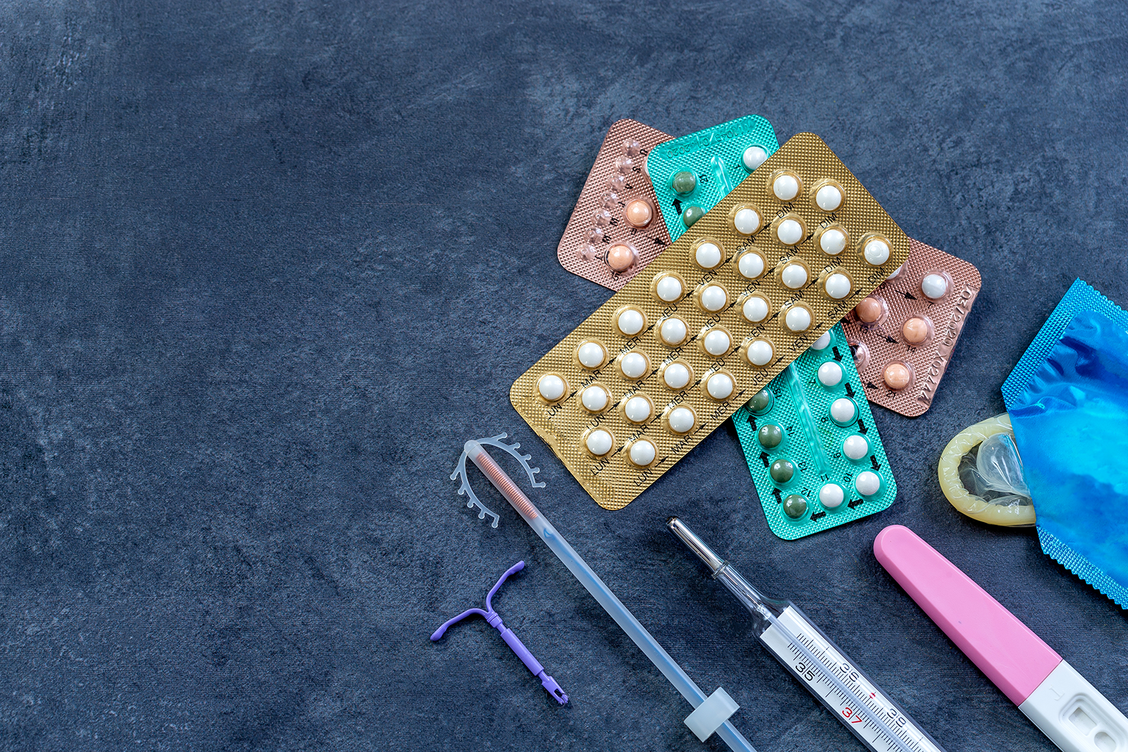 variations of birth control and thermometers on a blue background