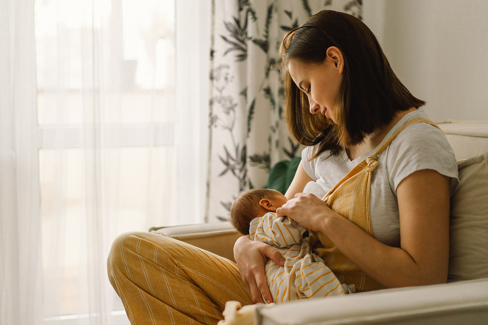 Woman breast feeding baby on a sofa chair
