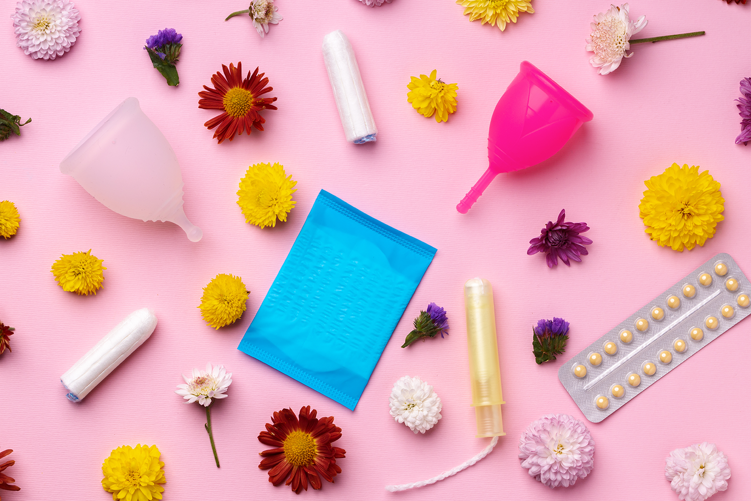 Menstrual products and flowers on a pink background