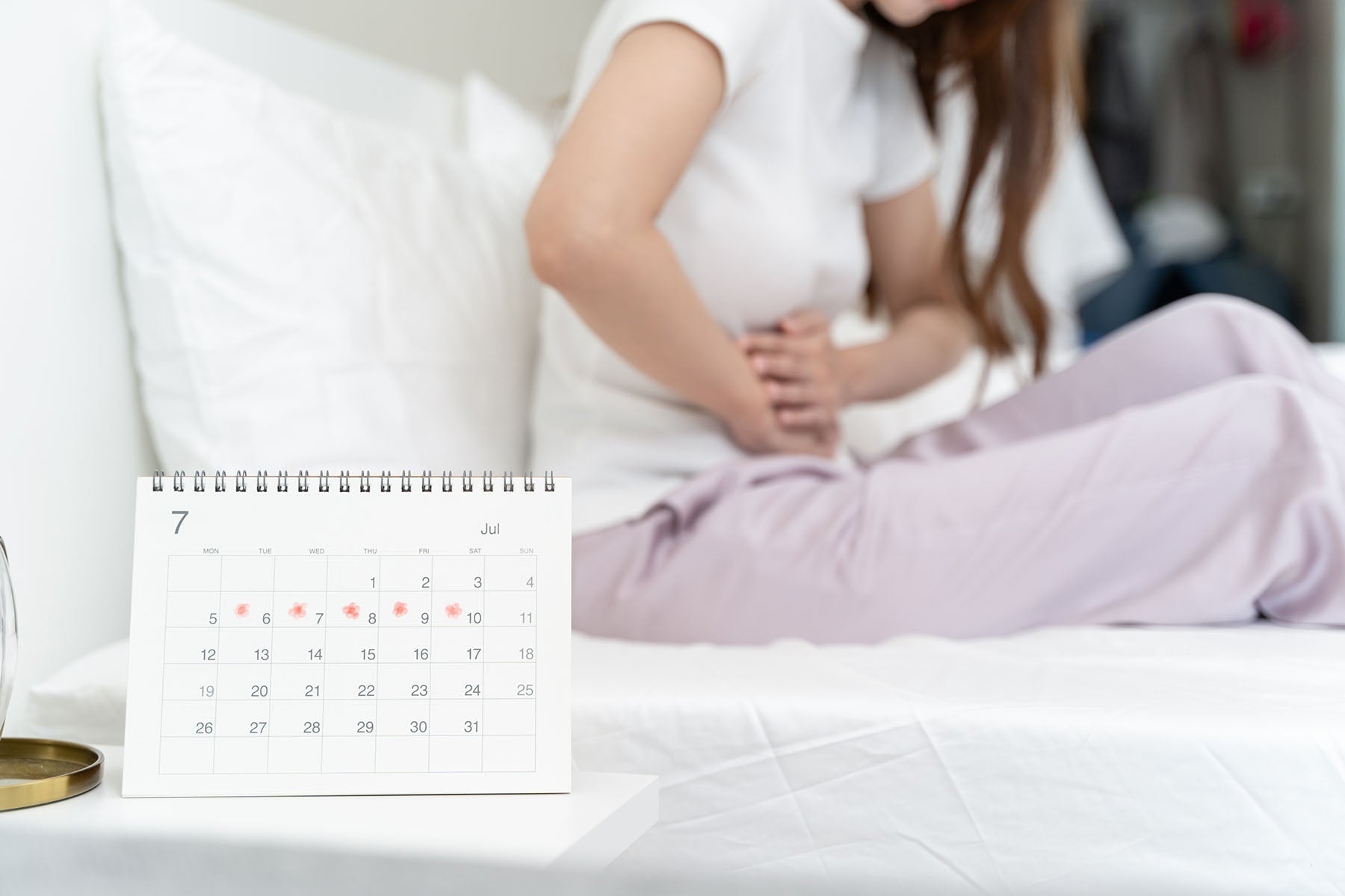 Woman sitting on a bed with a calendar in front of her
